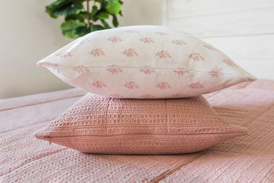 A pink zipper bedding made with the matching pillows stacked in the middle of the bed. 