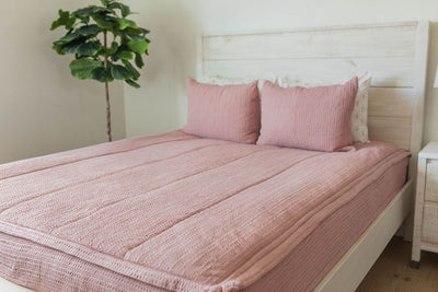 A bed made with pink woven zipper bedding and matching pillows.