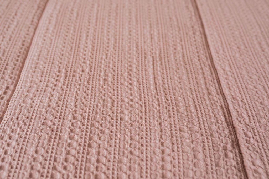 A close up view of the woven detail on pink zipper bedding.