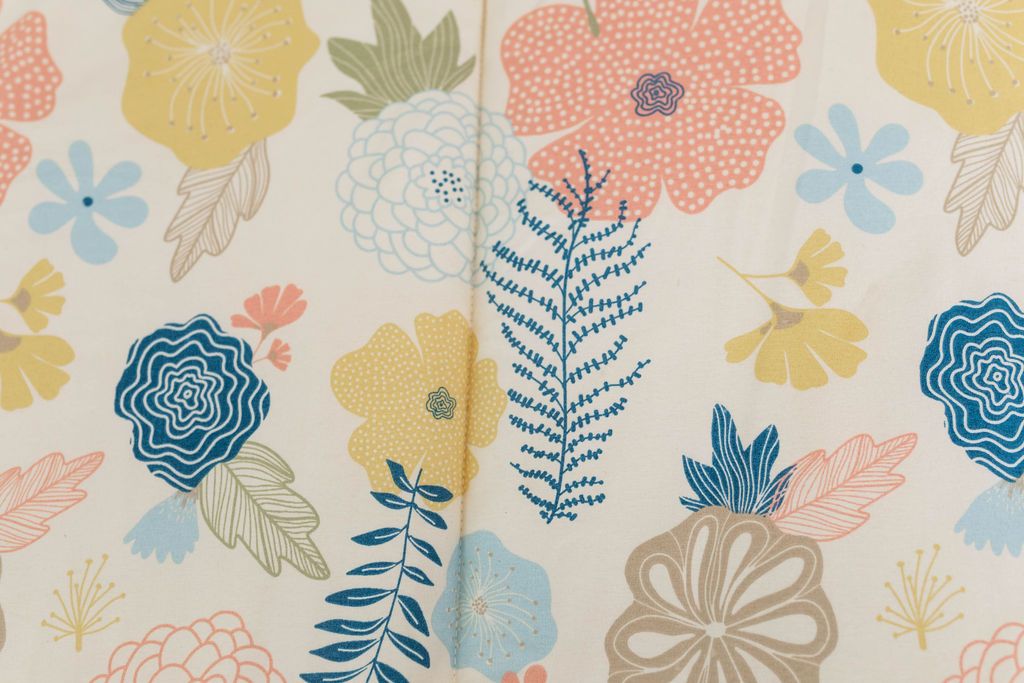 A close up of the print on a set of pink, yellow, and blue floral kids zipper bedding.