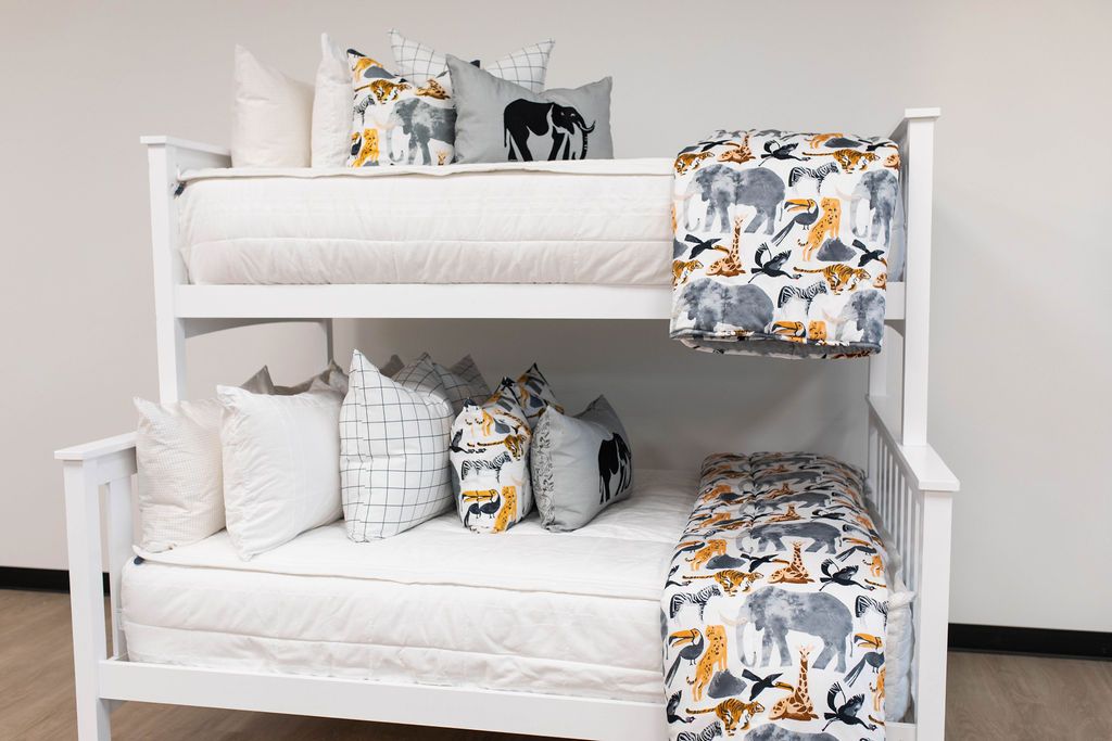 A standard bunk bed with both bunks made with white woven plaid zipper bedding and animal printed pillows and blankets.