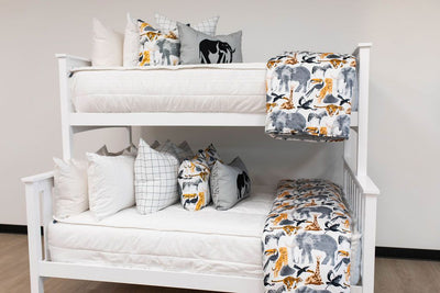 A standard bunk bed with both bunks made with white woven plaid zipper bedding and animal printed pillows and blankets.