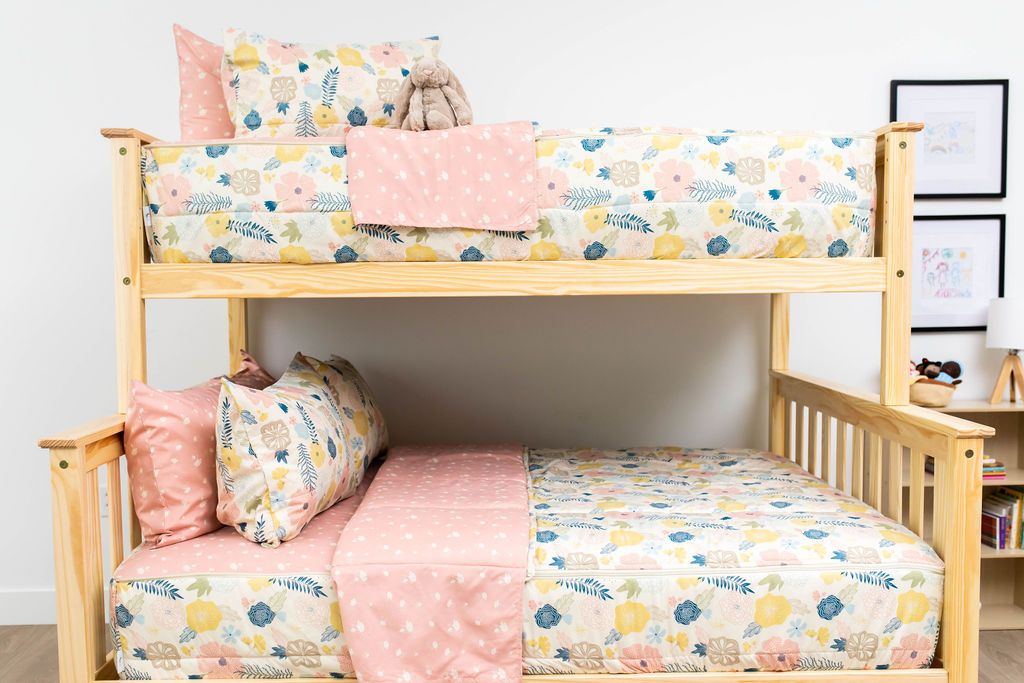 A bunk bed where both bunks are made with pink, yellow, and blue floral kids zipper bedding.