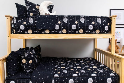 A bunk bed where both bunks are made with black planets and stars kids zipper bedding.