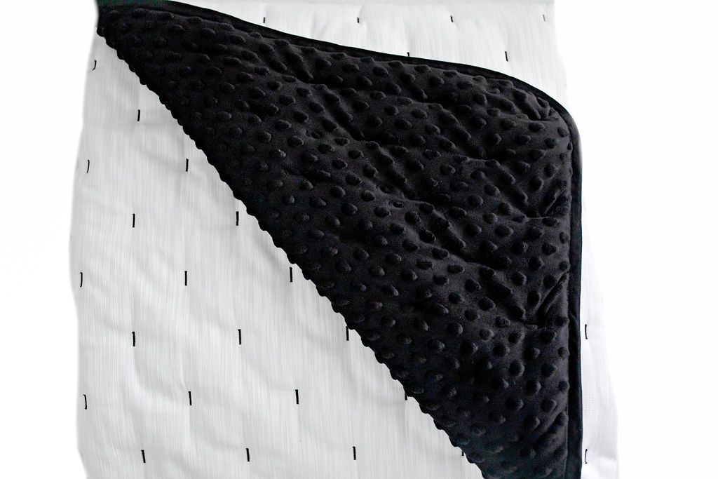 White blanket with black edge and small black lines with revealed black minky inner lining