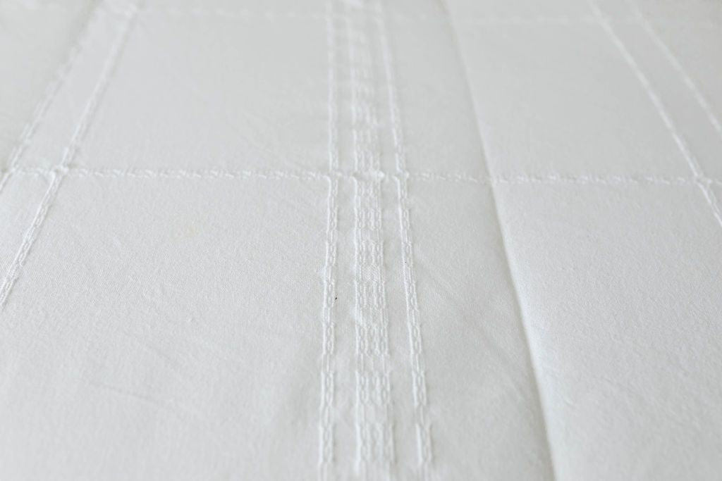 A close up of the woven plaid detail on white zipper bedding.