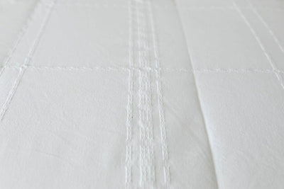 A close up of the woven plaid detail on white zipper bedding.