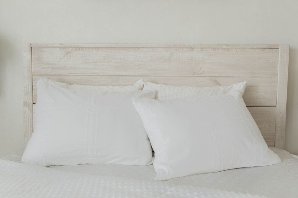 White pillowcases on a made bed with white zipper bedding and the comforter pulled back. 