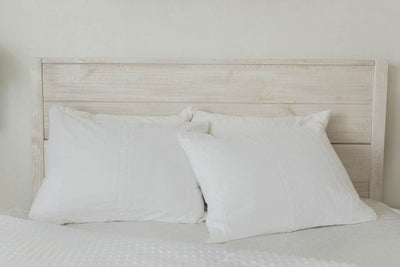 White pillowcases on a made bed with white zipper bedding and the comforter pulled back. 