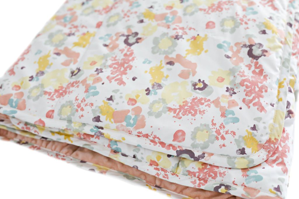 A blue, yellow, peach, and purple floral pattern folded blanket.