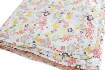 A blue, yellow, peach, and purple floral pattern folded blanket.