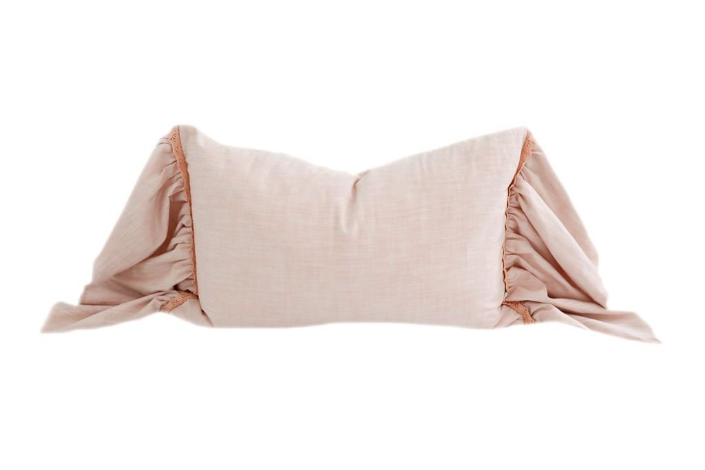 A pink lumbar ruffled pillow with lace details.
