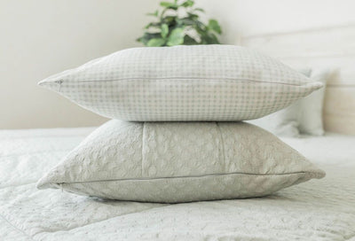 A close up of light green pillowcases stack on top of the matching zipper bedding. 