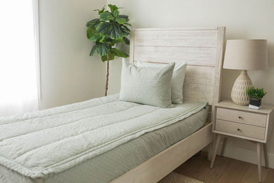 A twin bed made with soft honeycomb green textured zipper bedding.