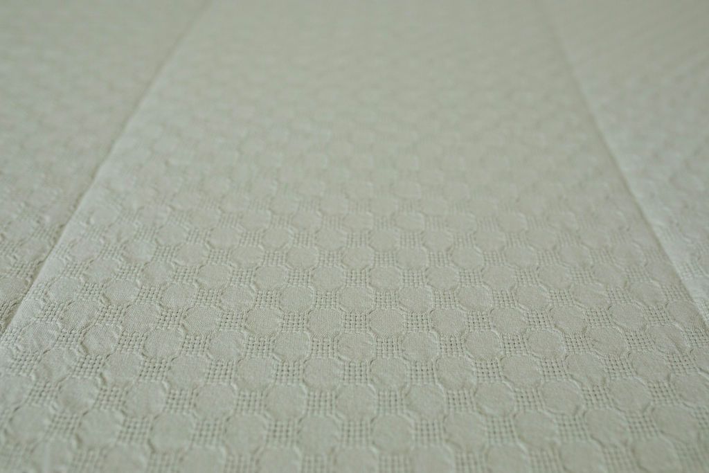 A close up detailed view of the honeycomb texture on sage green zipper bedding.