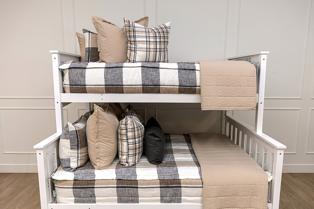 A bunk bed made with plaid zipper bedding with neutral accessories.