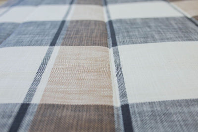 A close up view of a bed made with charcoal, cream and tan plaid zipper bedding.