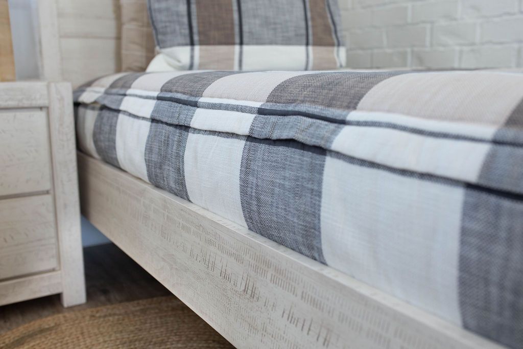 A close up side view of a bed made with cream, tan, and charcoal plaid zipper bedding.