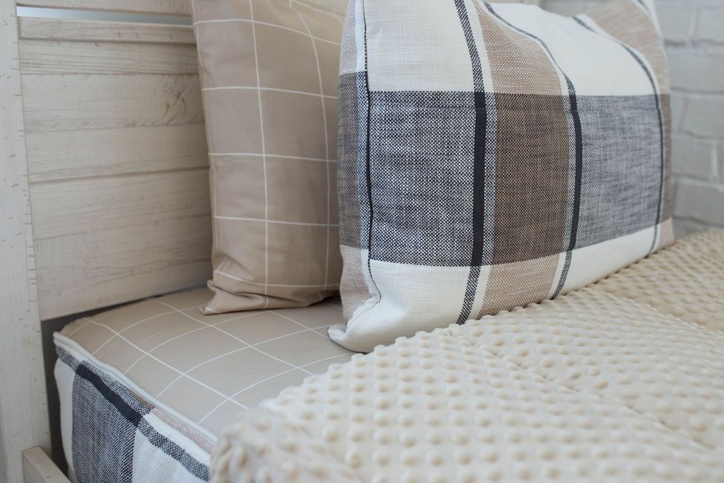 A tan, charcoal gray, and cream white zipper bedding made with matching pillows and the comforter pulled back to showcase the minky interior lining. 