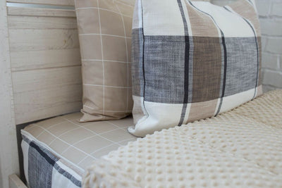 A tan, charcoal gray, and cream white zipper bedding made with matching pillows and the comforter pulled back to showcase the minky interior lining. 