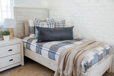 A twin bed made with charcoal, cream, and tan zipper bedding and neutral matching throw pillows and blanket.