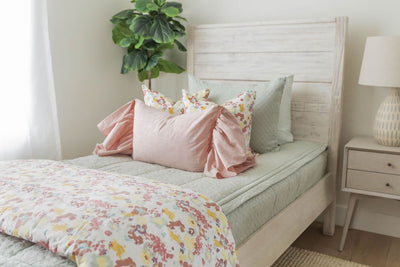 Sage green zipper bedding with sage green pillow cases and shams. Decorated with pastel floral pillows and matching blanket. Pink sham pillow
