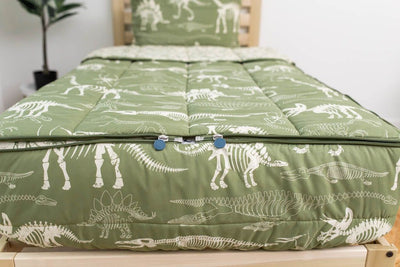The foot of a bed made with olive green dinosaur fossils kids zipper bedding showing where the two zippers are located.