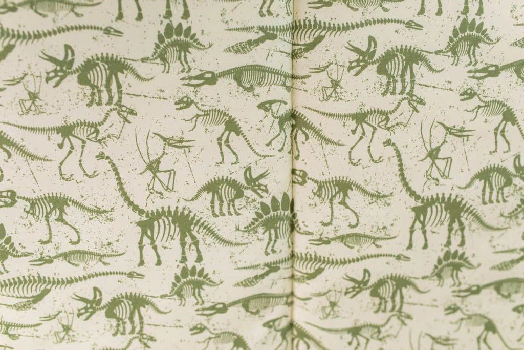 A close up of the interior of a set of olive green dinosaur fossils zipper bedding.