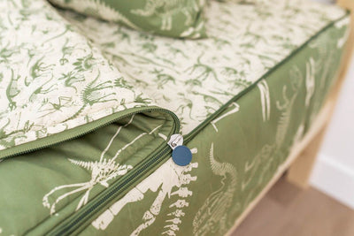 A close up on the zipper feature of a set of olive green dinosaur fossils kids zipper bedding.
