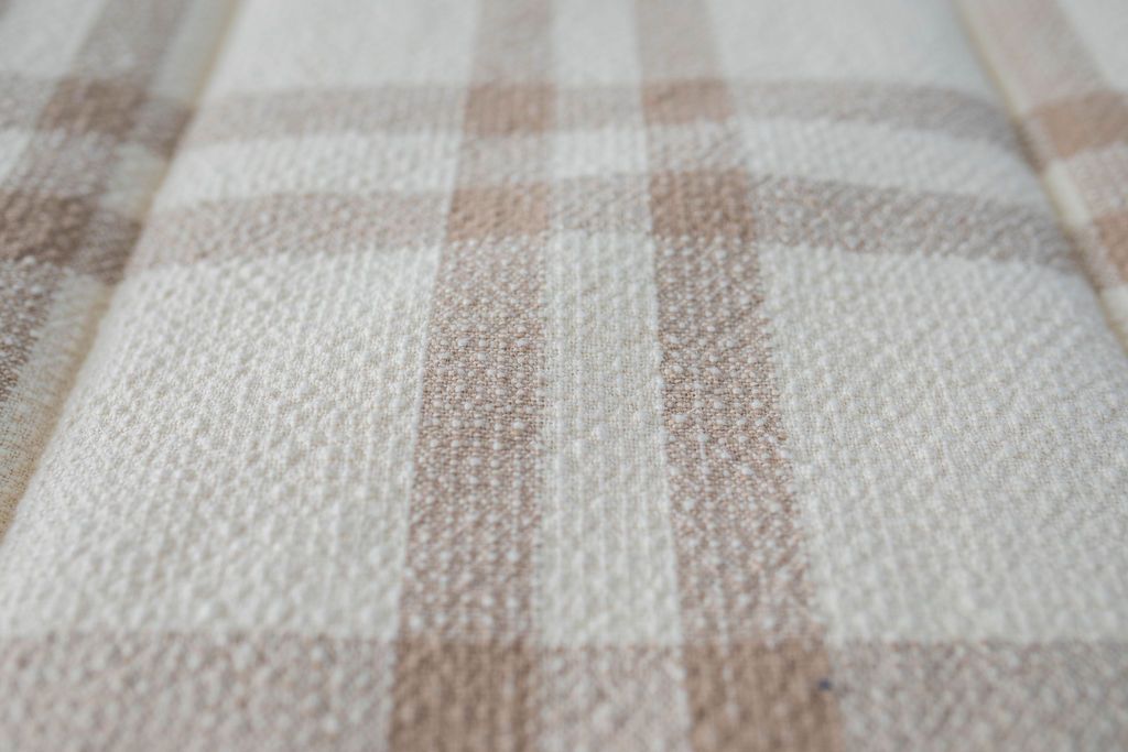 Close up view of texture of cream and brown plaid zipper bedding.