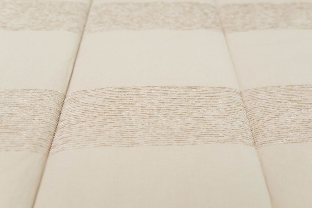 A close up of the texture and striped pattern on tan zipper bedding.