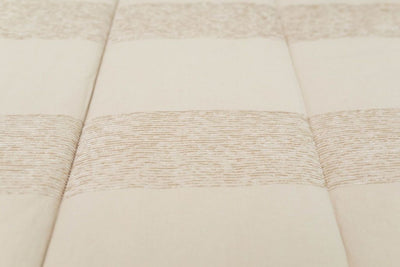 A close up of the texture and striped pattern on tan zipper bedding.