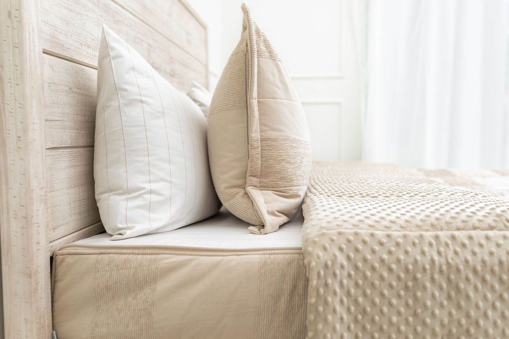 A side view of a bed made with tan faded stripes zipper bedding with the top unzipped halfway down the bed and the comforter folded down.
