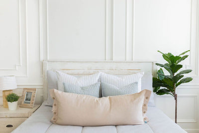 A close up view of a bed made with light gray waffle texture zipper bedding and an assortment of neutral and striped pillows.