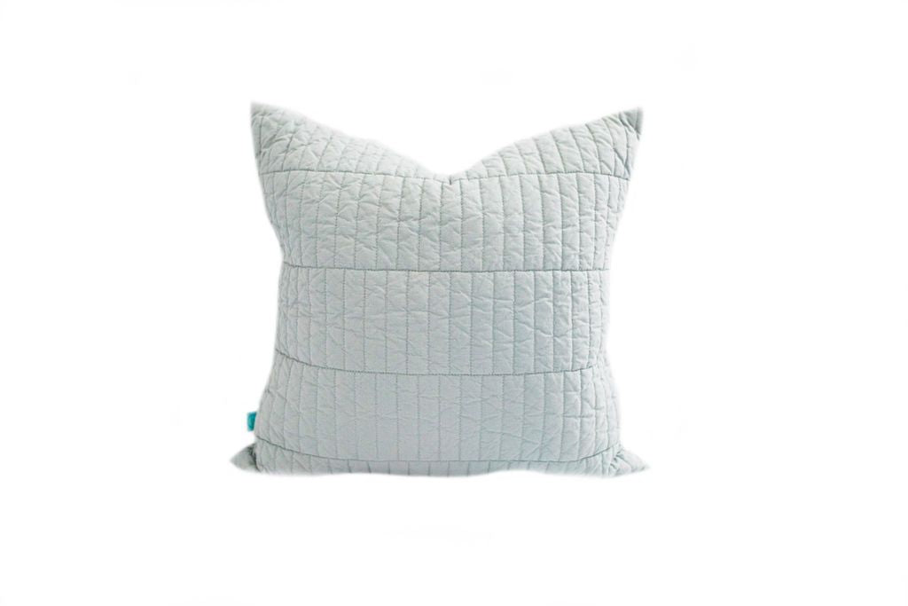 A light blue quilted pillow on a white background.