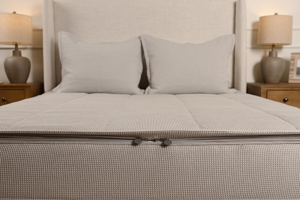 End of bed showing double zippers on gray grid zipper bedding.