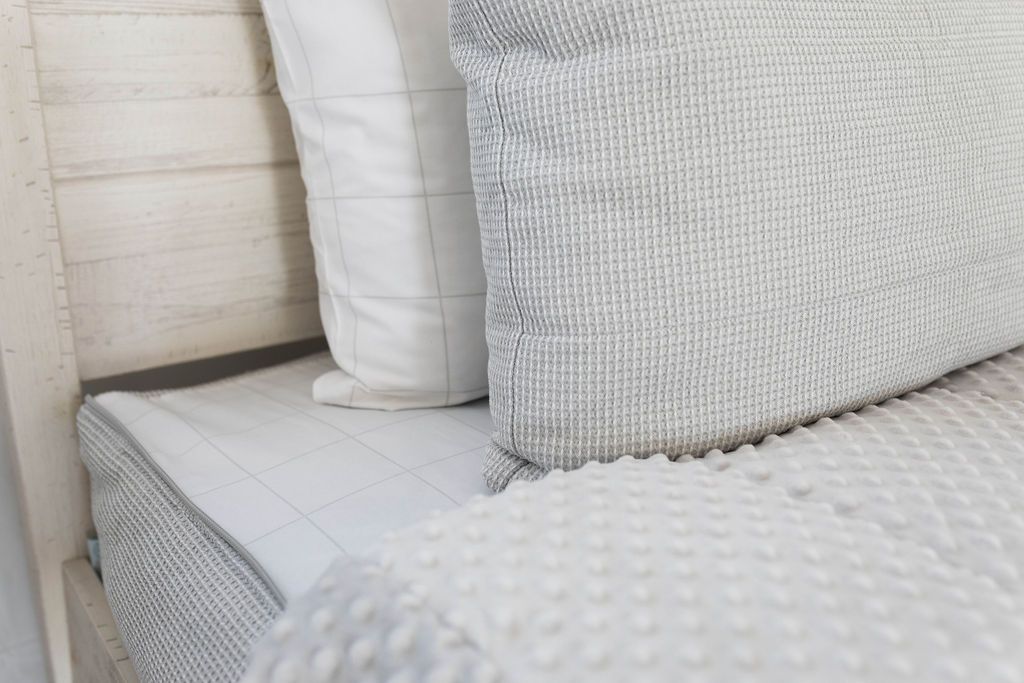 White and gray pillowcases on a gray zipper bedding with the comforter pulled back showing minky lining.