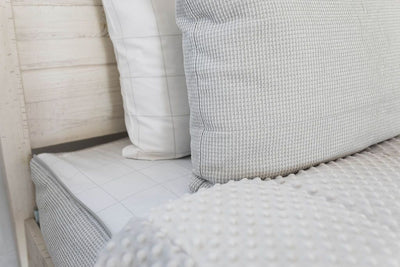 White and gray pillowcases on a gray zipper bedding with the comforter pulled back showing minky lining.