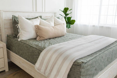 Green zipper bedding with matching pillowcases and shams. Decorated with white pillows, cream lumbar pillow, and white blanket with cream stripes