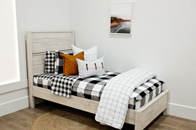 twin bed with black and white buffalo plaid bedding with white and black grid euro, faux leather pillows, white and black striped lumbar with faux lather buckles and white and black grid pattered blanket