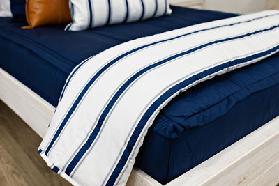 Enlarged view of a white and navy blue striped blanket on navy blue bedding.