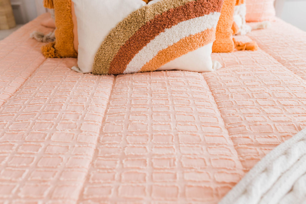 peach bedding with textured rectangle detail with rainbow lumbar pillow