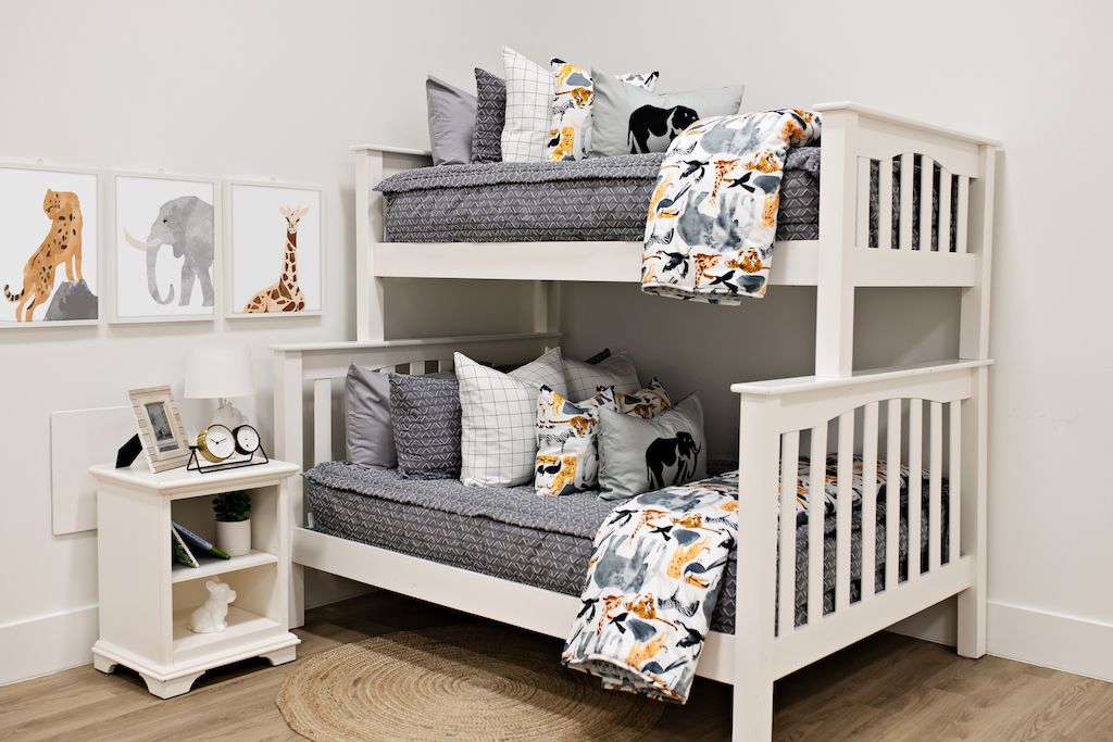 bunk bed with gray textured bedding and white and black grid patterned euro, safari animal print pillow, gray lumbar with embroidered elephant and safari animal print blanket
