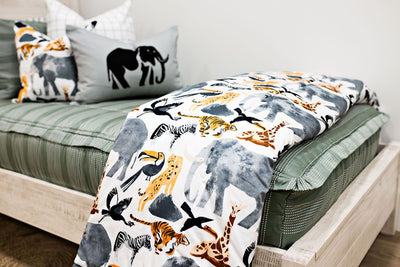 Enlarged view of a white blanket with jungle animals on sage green  and white striped bedding.