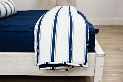 Enlarged side view of a white and navy blue striped blanket on navy blue bedding.