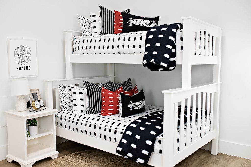 bunk bed with white and black dashed lined bedding with White and black striped euro, red and white dashed pillow, black lumbar with white longboard print, black blanket with white dashed lines at the foot of the bed
