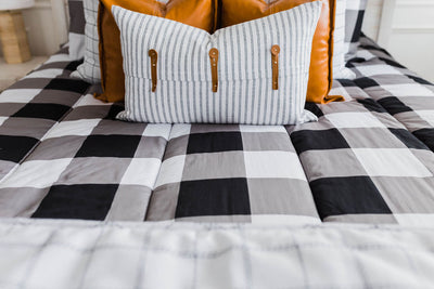 Black and white buffalo plaid bedding with white and black grid euro, faux leather pillows, white and black striped lumbar with faux lather buckles and white and black grid pattered blanket