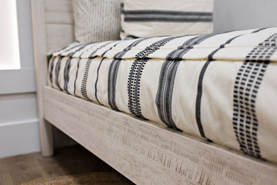 side view of cream and black woven striped bedding
