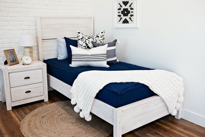 twin bed with navy zipper bedding and cow rawhide print euro, black and cream stiped pillow, cream and black striped lumbar, cream knitted chenille throw