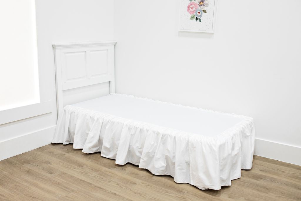 White twin size bed with a white bed skirt.